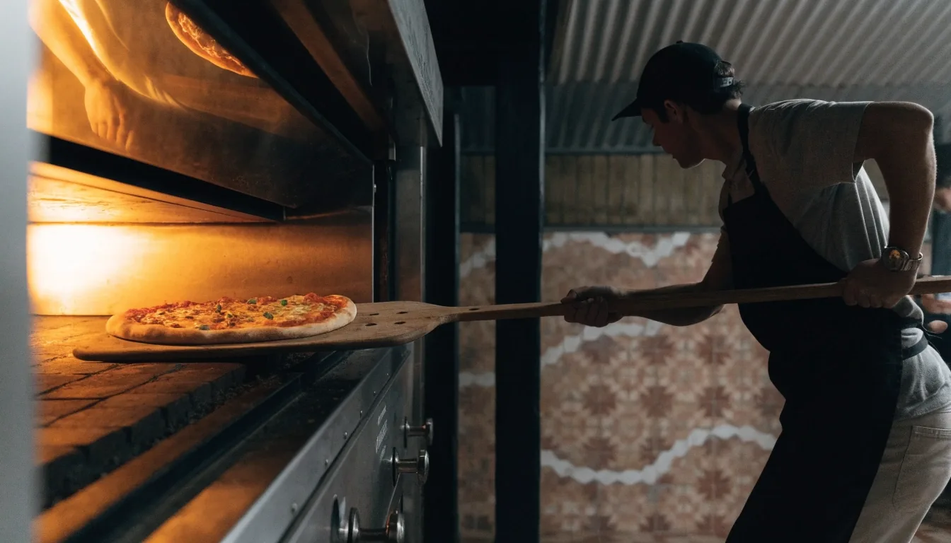 Fresh pizza dough being stretched by hand inside a Dion's kitchen