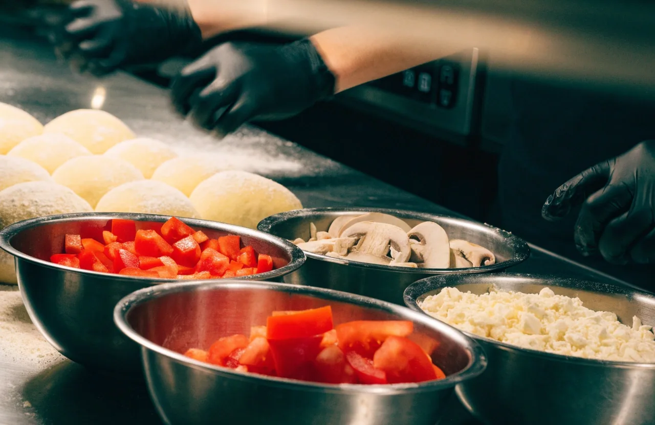 Fresh toppings and dough preparation at a Dion's prep station
